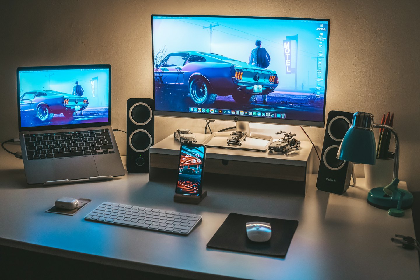 Modern desk setup with laptop, monitor, and toy cars.